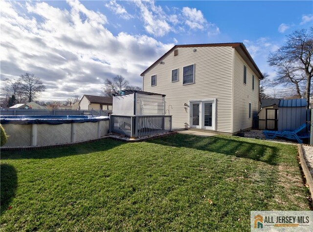 back of property featuring a pool side deck, a storage shed, and a lawn