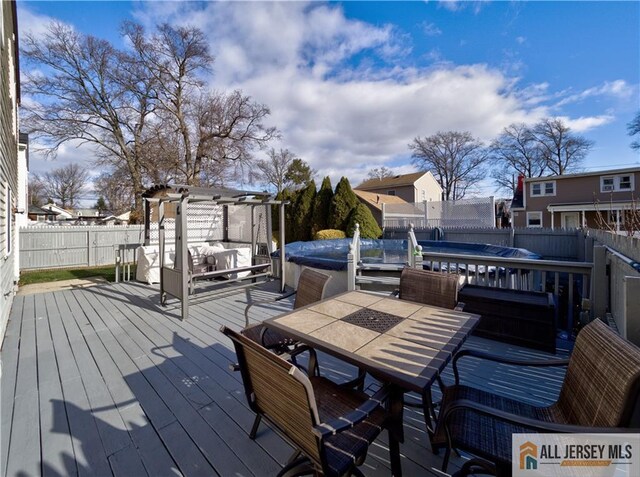 wooden deck with a hot tub and a pergola