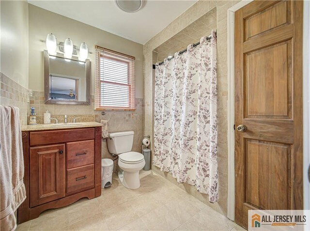 bathroom featuring curtained shower, tile walls, vanity, toilet, and tile patterned floors