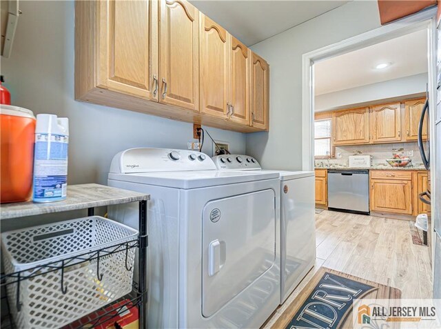 clothes washing area featuring cabinets, washer and clothes dryer, and light hardwood / wood-style floors