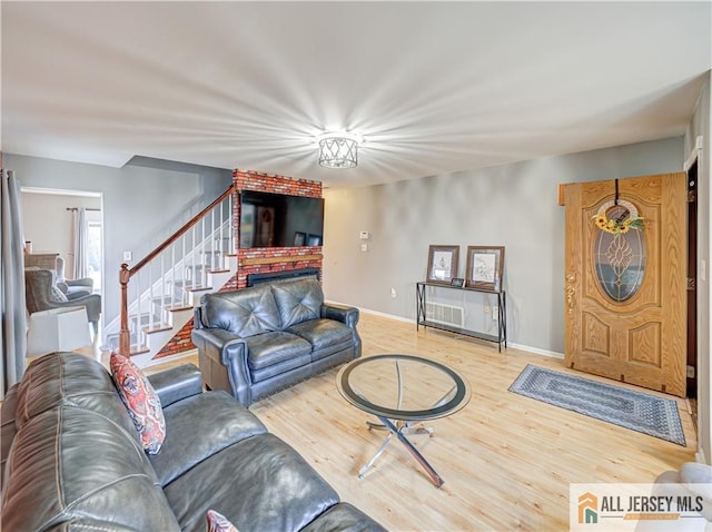 living area with a fireplace, stairway, baseboards, and wood finished floors