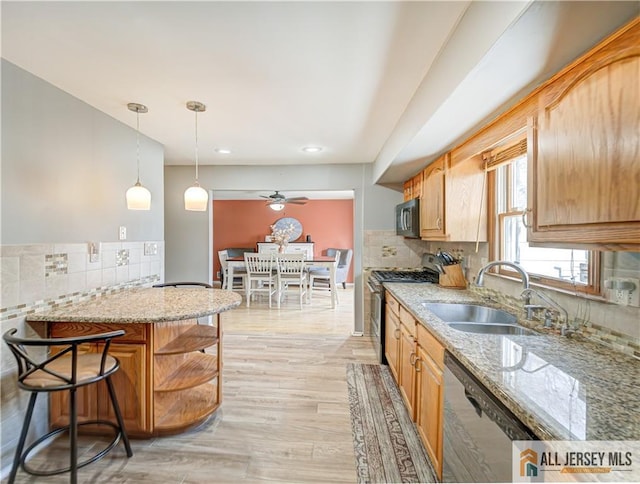 kitchen featuring sink, a breakfast bar area, light stone counters, appliances with stainless steel finishes, and kitchen peninsula