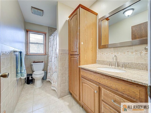 bathroom featuring tile walls, tile patterned flooring, vanity, walk in shower, and toilet