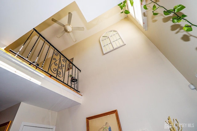 staircase with a ceiling fan, a skylight, and a towering ceiling