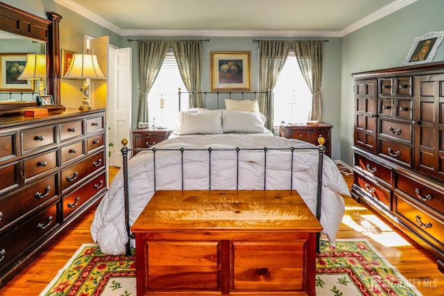 bedroom featuring ornamental molding, multiple windows, and wood finished floors