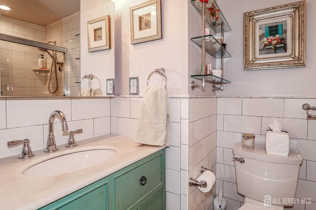 full bathroom with a wainscoted wall, tile walls, toilet, vanity, and tiled shower