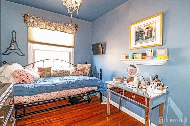 bedroom with a chandelier, wood finished floors, and baseboards