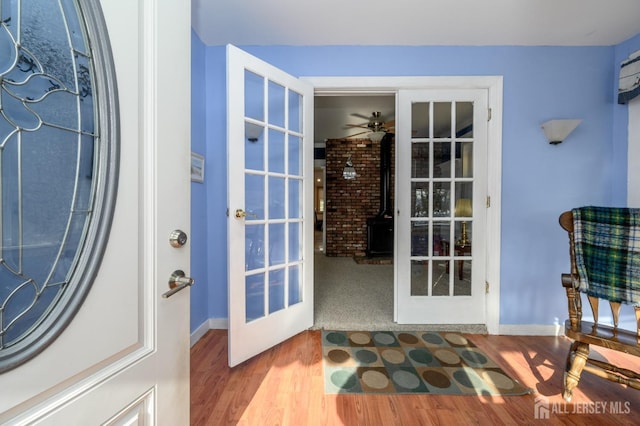 doorway to outside with french doors, a wood stove, hardwood / wood-style floors, and ceiling fan