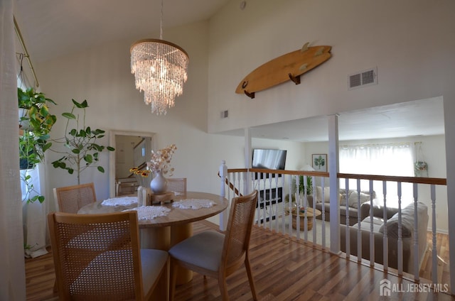 dining room featuring a towering ceiling, dark hardwood / wood-style floors, and an inviting chandelier