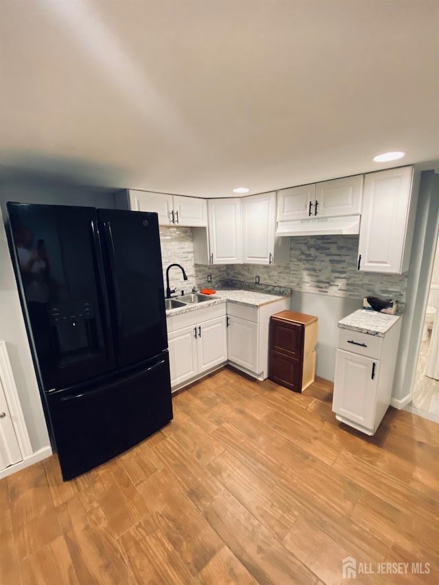 142 Liberty St, Fords, NJ 08863 - kitchen with black refrigerator with ice dispenser, under cabinet range hood, decorative backsplash, white cabinets, and light wood finished floors