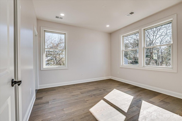 empty room with visible vents, plenty of natural light, and wood finished floors