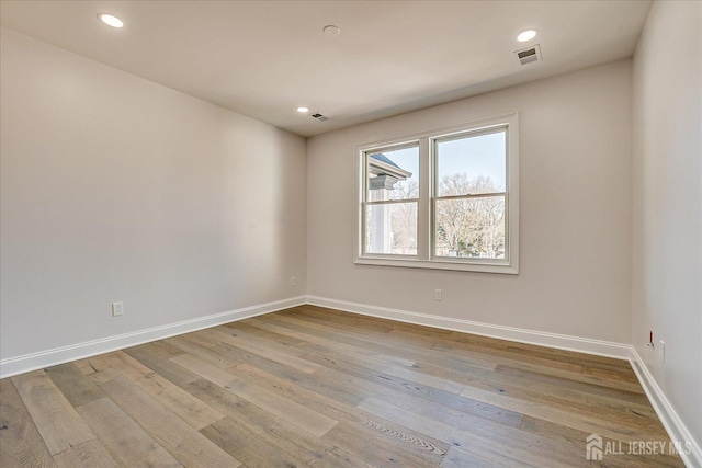 unfurnished room featuring visible vents, baseboards, and wood-type flooring