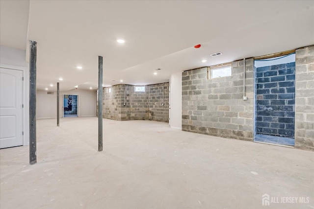 below grade area featuring visible vents, recessed lighting, and concrete block wall