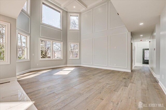 interior space featuring light wood finished floors, a decorative wall, plenty of natural light, and baseboards