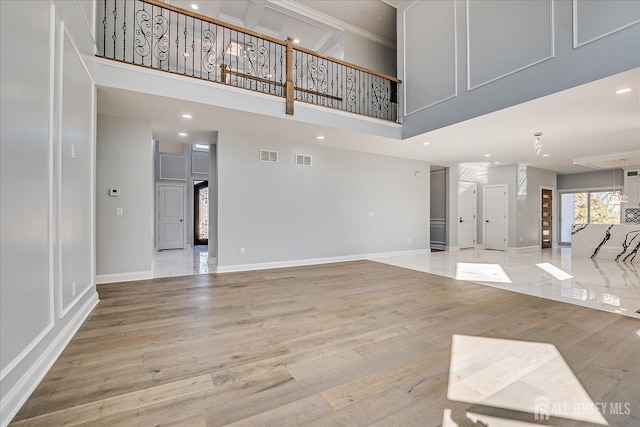 unfurnished living room featuring visible vents, baseboards, and wood finished floors