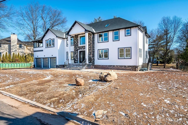 view of front of home featuring stucco siding, a shingled roof, and a garage