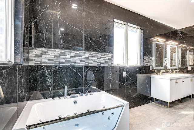 full bath with vanity, tile walls, and a tub with jets