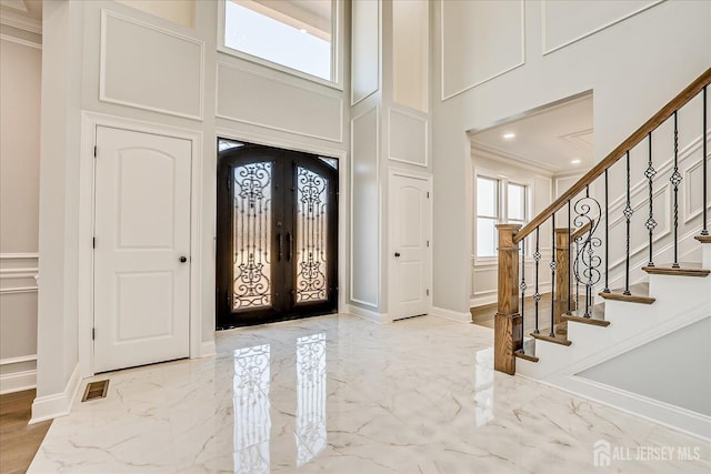 entryway with visible vents, stairs, french doors, a decorative wall, and marble finish floor