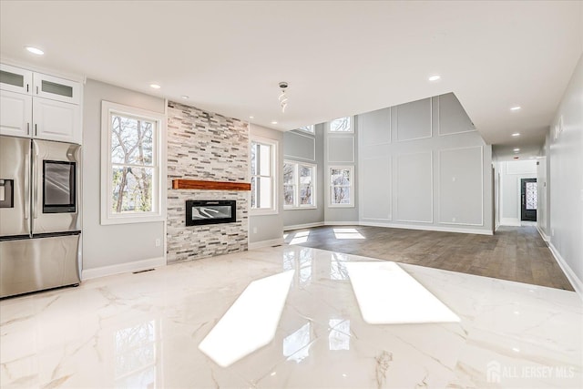 living room with a wealth of natural light, marble finish floor, recessed lighting, and a fireplace