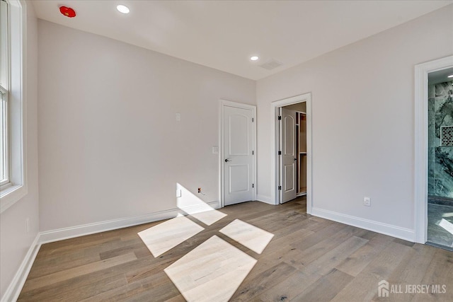 empty room featuring recessed lighting, wood finished floors, visible vents, and baseboards