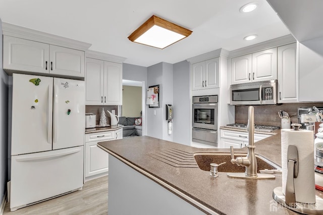 kitchen featuring white cabinets, decorative backsplash, stainless steel appliances, and light hardwood / wood-style flooring