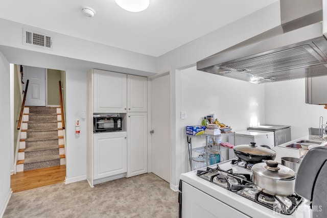 kitchen with white cabinets, wall chimney range hood, sink, and white stove