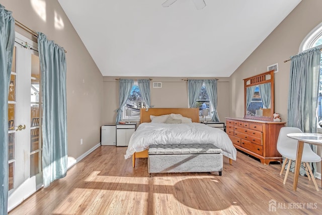 bedroom featuring vaulted ceiling, light hardwood / wood-style flooring, and multiple windows