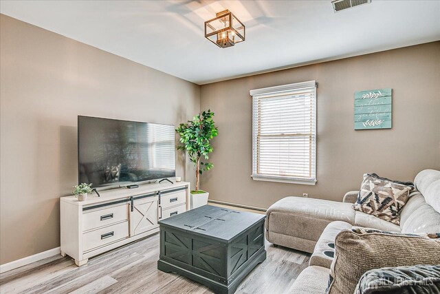 living area with light wood finished floors, a baseboard radiator, visible vents, and baseboards