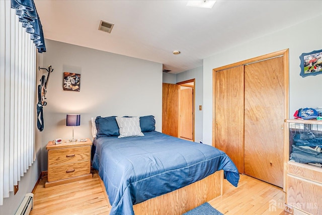 bedroom featuring light wood-style flooring, a closet, a baseboard radiator, and visible vents