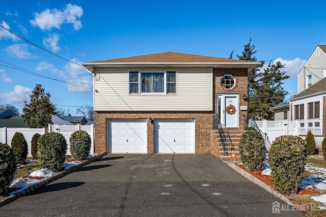 view of front of property with brick siding, an attached garage, fence, and aphalt driveway