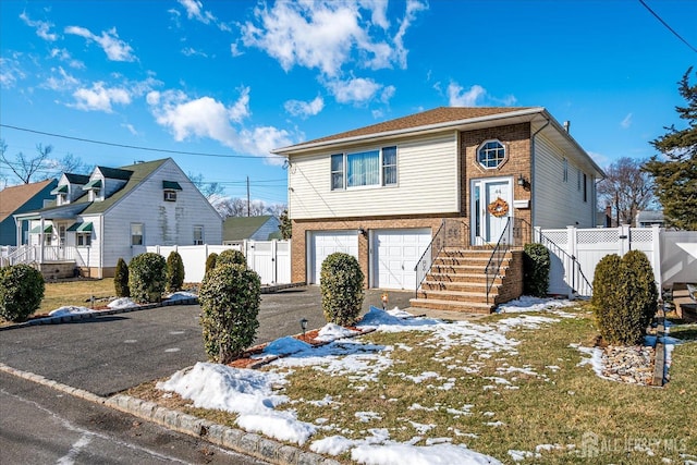 view of front of home featuring brick siding, an attached garage, fence, and aphalt driveway