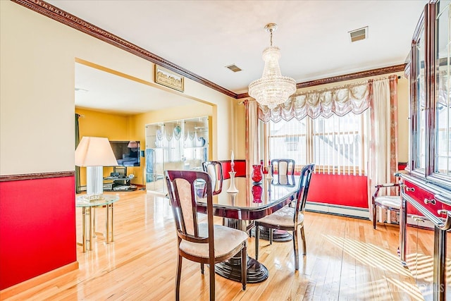 dining room featuring hardwood / wood-style floors, crown molding, a chandelier, and a baseboard heating unit