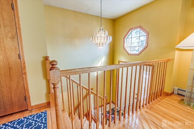 staircase with wood-type flooring, a chandelier, and a baseboard radiator