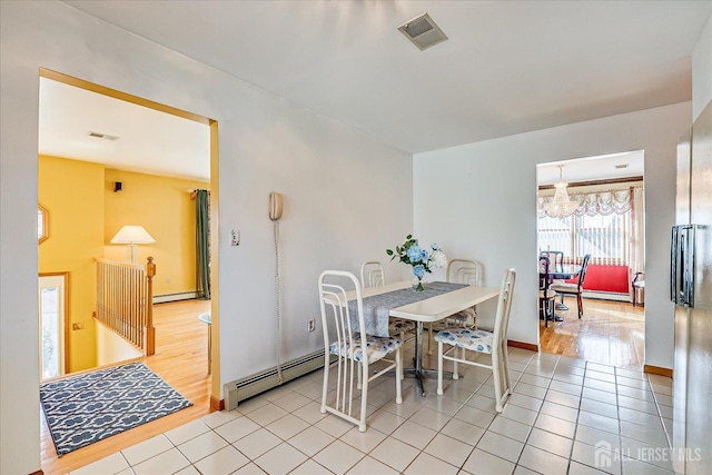 dining space with baseboard heating, a chandelier, and light tile patterned floors