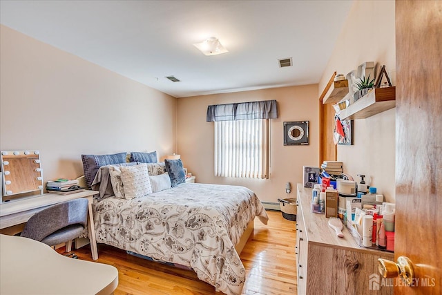 bedroom with a baseboard radiator and light hardwood / wood-style flooring