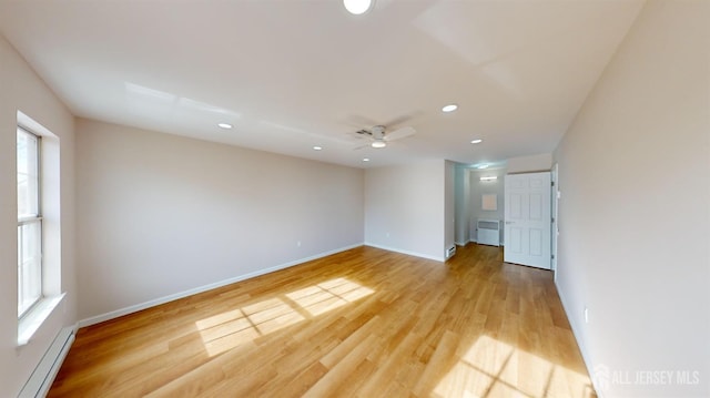 spare room with ceiling fan, a baseboard heating unit, and light hardwood / wood-style flooring