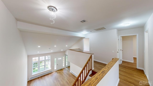 corridor with a baseboard heating unit, vaulted ceiling with beams, and light hardwood / wood-style flooring