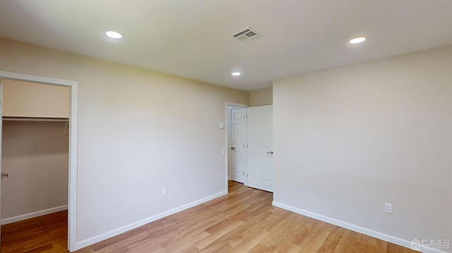 unfurnished bedroom with light wood-type flooring, a spacious closet, and a closet