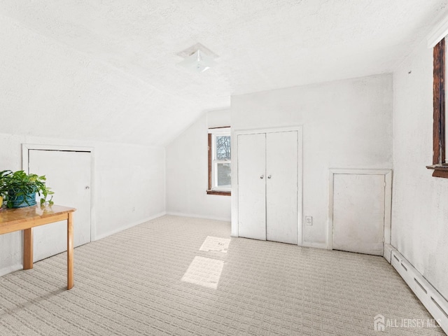 additional living space with a baseboard heating unit, carpet floors, a textured ceiling, and lofted ceiling