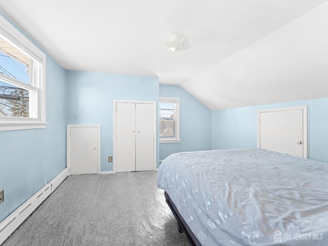 bedroom with a baseboard heating unit, a closet, vaulted ceiling, and carpet floors