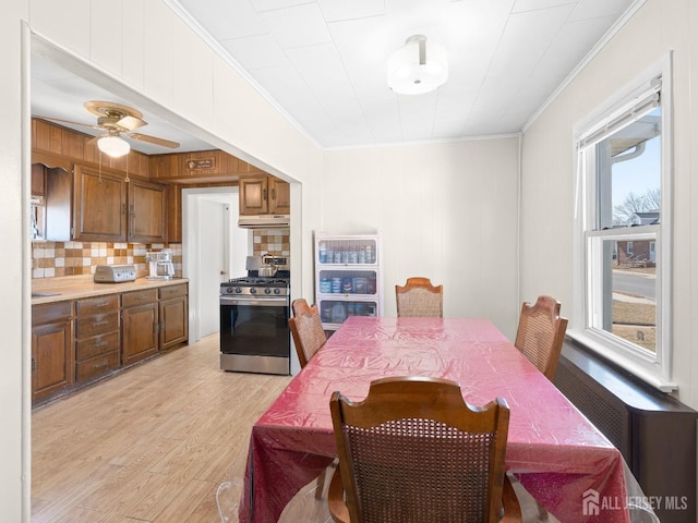 dining area featuring ceiling fan, light wood-style floors, and crown molding