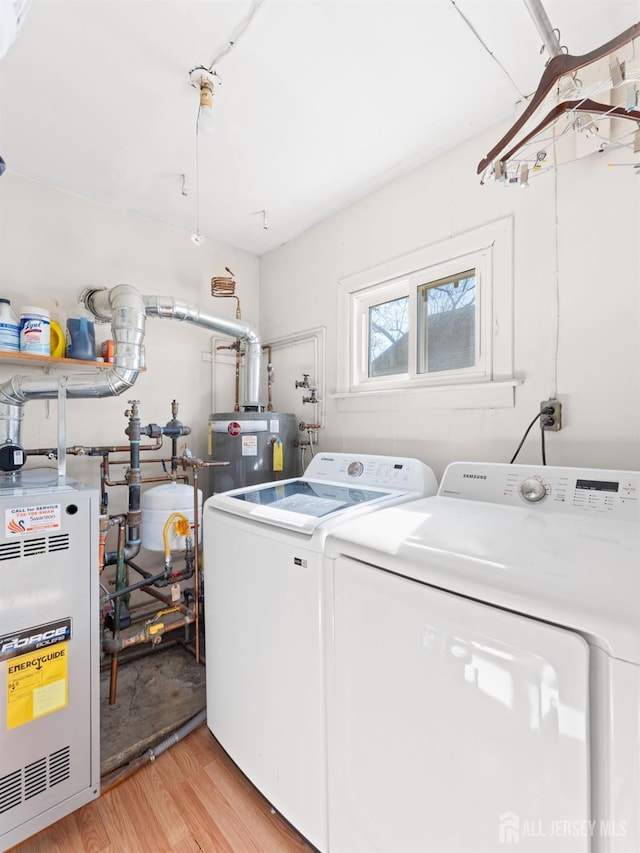 laundry room with a heating unit, washer and clothes dryer, laundry area, water heater, and light wood-style flooring
