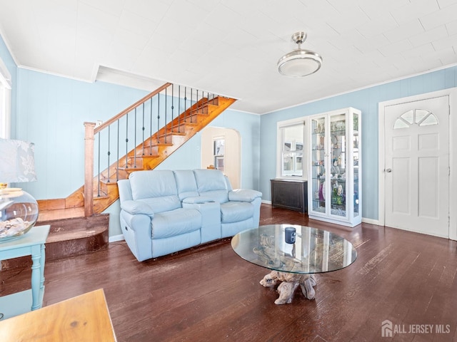 living room with wood finished floors, arched walkways, baseboards, stairway, and crown molding