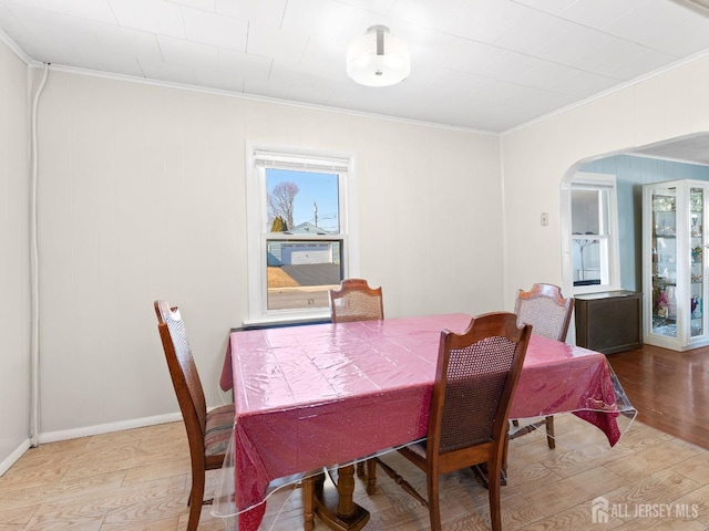 dining area with a wealth of natural light, light wood-type flooring, and ornamental molding