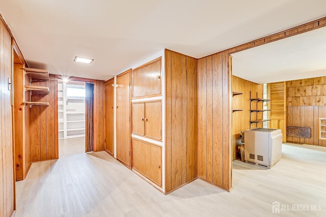 hallway with light wood-style floors and wooden walls