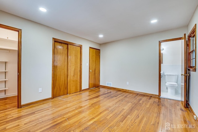 unfurnished bedroom with light wood-style flooring, visible vents, multiple closets, and recessed lighting