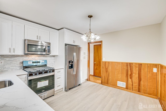 kitchen with visible vents, light stone countertops, stainless steel appliances, white cabinetry, and pendant lighting