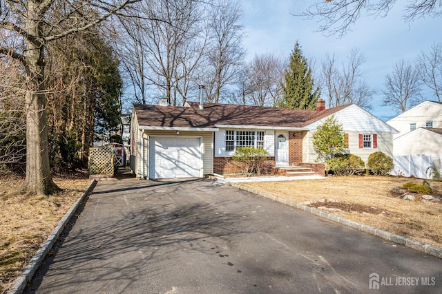 single story home featuring aphalt driveway, brick siding, a chimney, and a garage