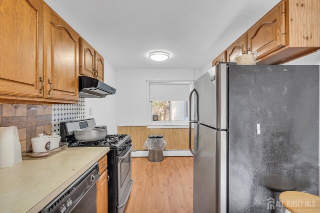 kitchen with decorative backsplash, light wood-type flooring, a baseboard heating unit, and appliances with stainless steel finishes