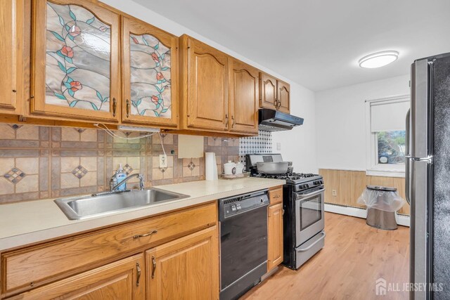 kitchen featuring sink, light hardwood / wood-style flooring, decorative backsplash, baseboard heating, and appliances with stainless steel finishes